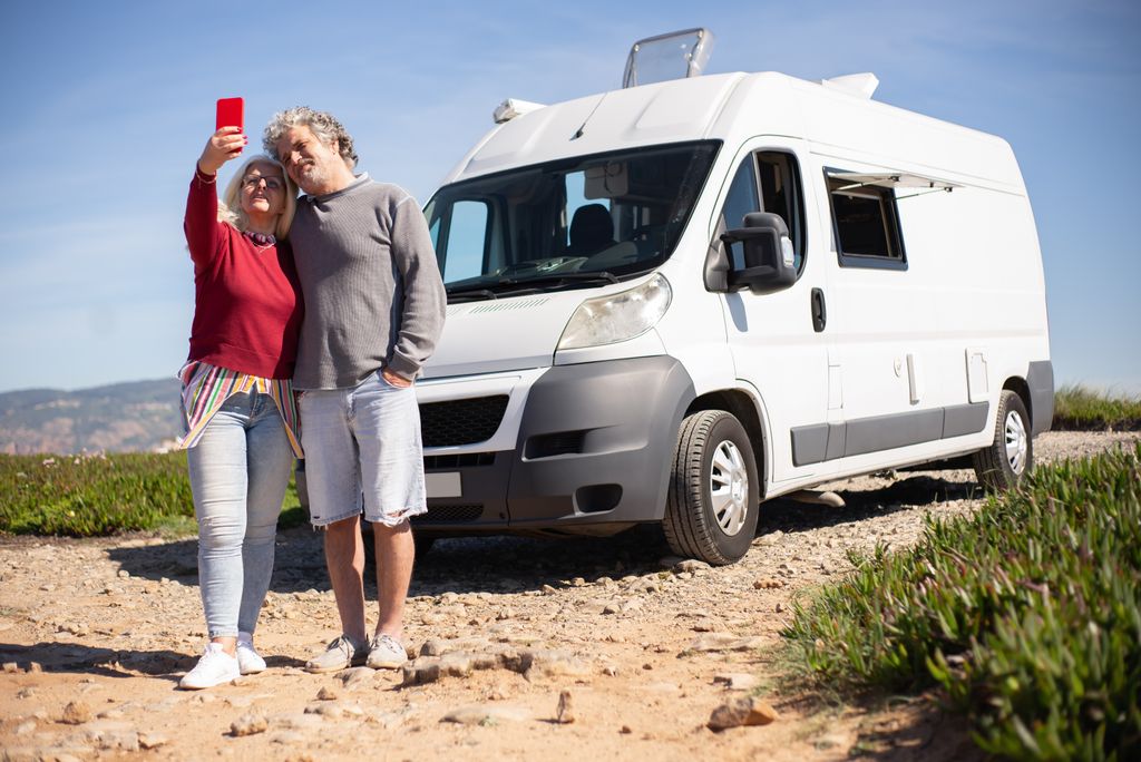 Couple taking a selfie beside their motorhome